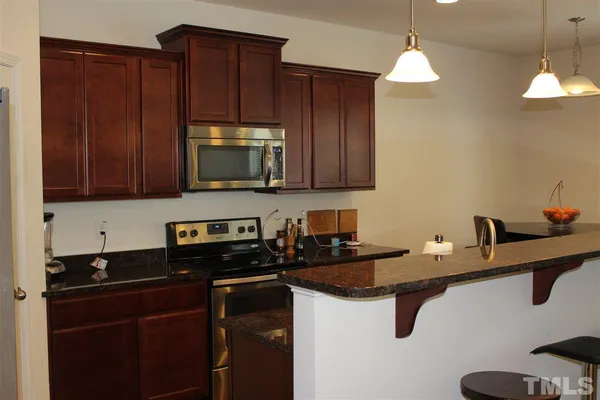 a kitchen with granite countertop a sink a stove and cabinets