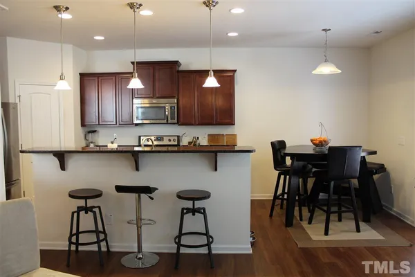 a kitchen with stainless steel appliances granite countertop a table chairs in it and wooden floors