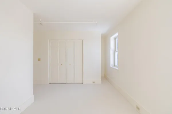 a view of an empty room with wooden floor and window