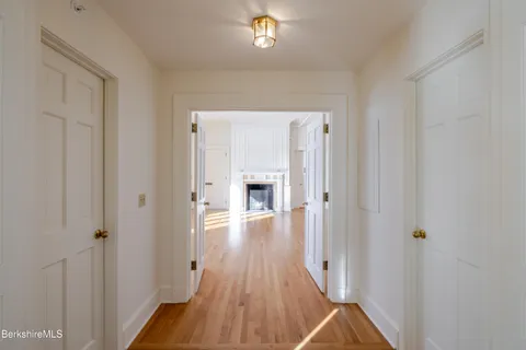 a view of a hallway with wooden floor and a bathroom