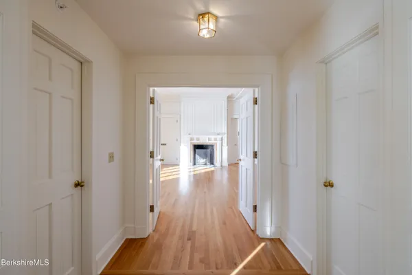a view of a hallway with wooden floor and a bathroom