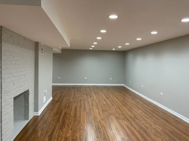 an empty room with wooden floor and a fireplace