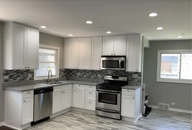 a kitchen with stainless steel appliances granite countertop a stove a sink and a microwave