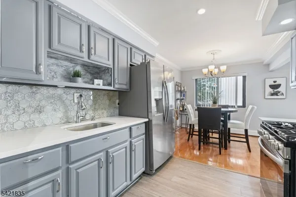 a kitchen with stainless steel appliances granite countertop a refrigerator a sink dishwasher a dining table and chairs with wooden floor