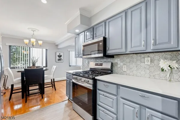a kitchen with stainless steel appliances granite countertop a stove a sink a microwave cabinets and a dining table