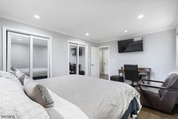 a bedroom with a bed a flat screen tv and a a large window