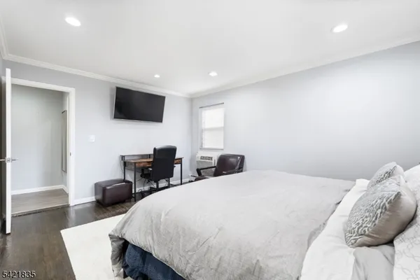 a bedroom with a bed a tv and wooden floor