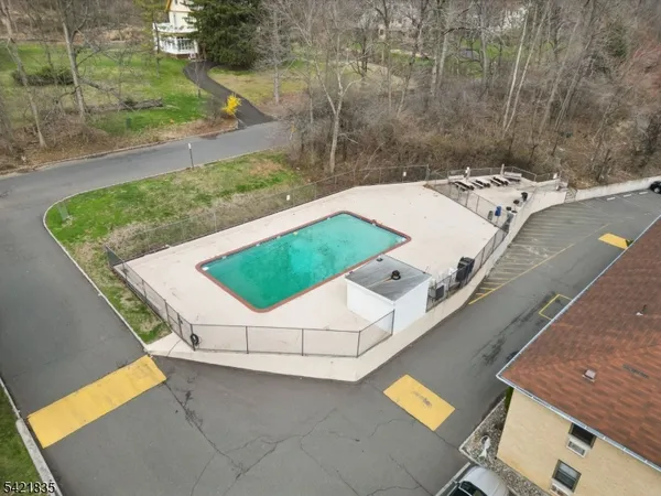 an aerial view of a house with swimming pool and large trees