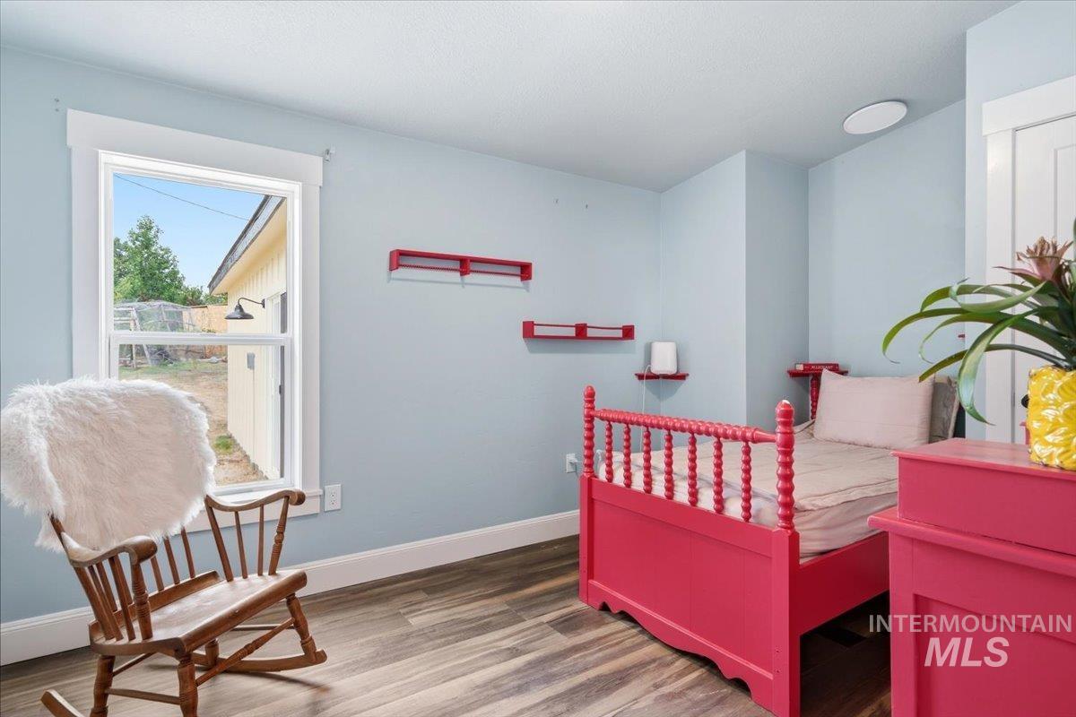 17114 Goodson Road Caldwell, ID 83607 - Photo 23 of 47 Bright room featuring a prominent window, wood-finish flooring, white trim, and a flush-mount ceiling light