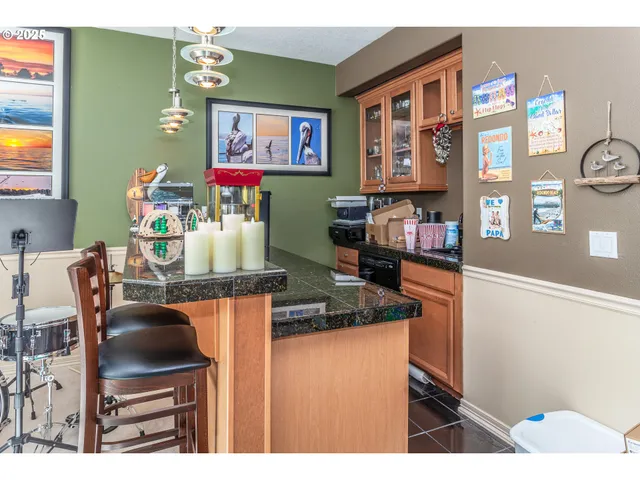 a kitchen area with stainless steel appliances granite countertop a dining table and chairs with wooden floor