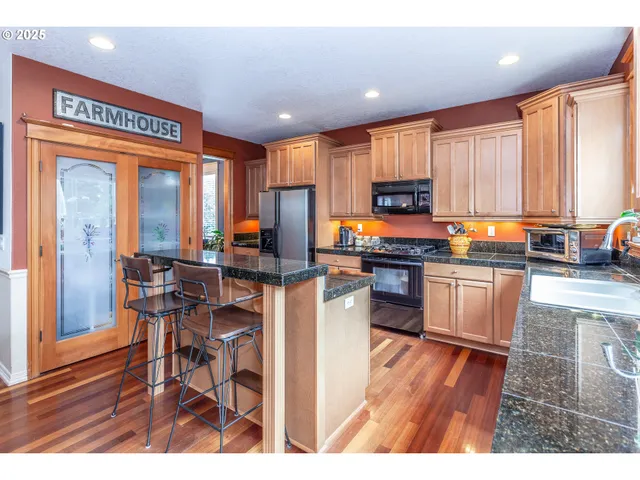 a kitchen with a refrigerator a stove a sink dishwasher with a dining table and chairs with wooden floor