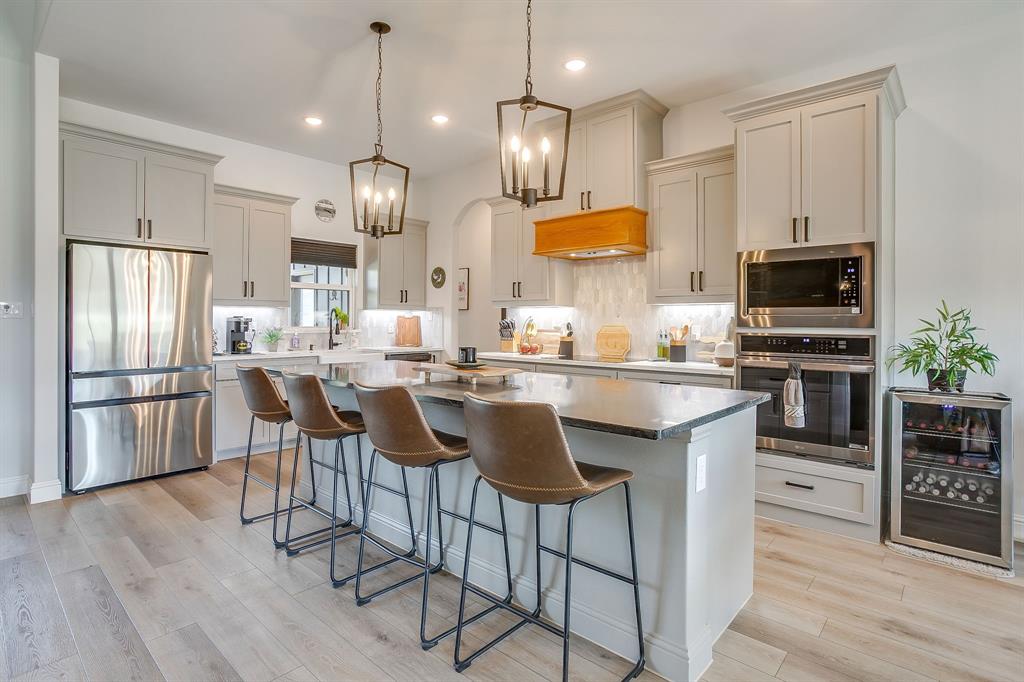 1040 Rose Court Nemo, TX 76070 - Photo 13 of 40 a kitchen with stainless steel appliances kitchen island granite countertop a refrigerator a stove a sink a dining table and chairs with wooden floor