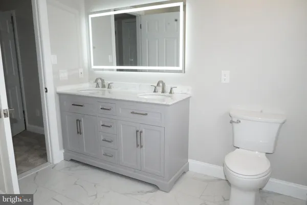 a bathroom with a granite countertop toilet sink and mirror