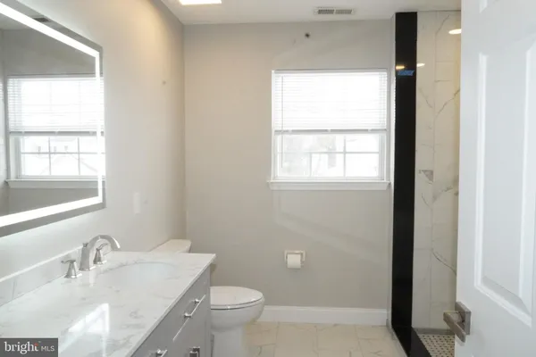 a bathroom with a granite countertop sink a toilet and a window
