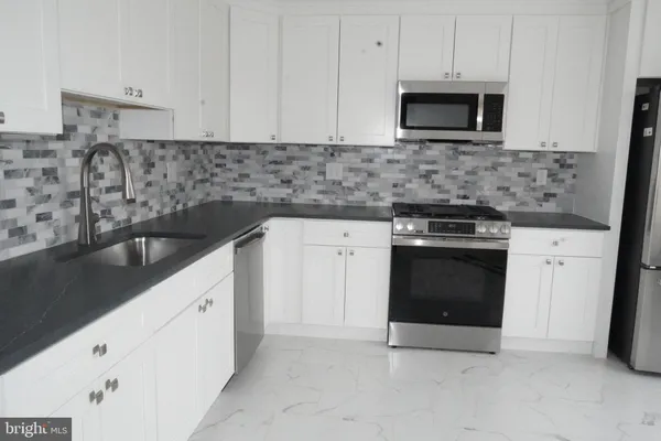 a kitchen with granite countertop white cabinets and stainless steel appliances