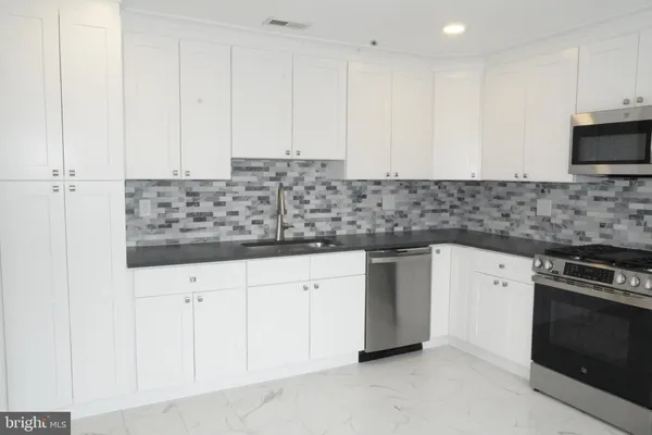 a kitchen with granite countertop white cabinets and stainless steel appliances