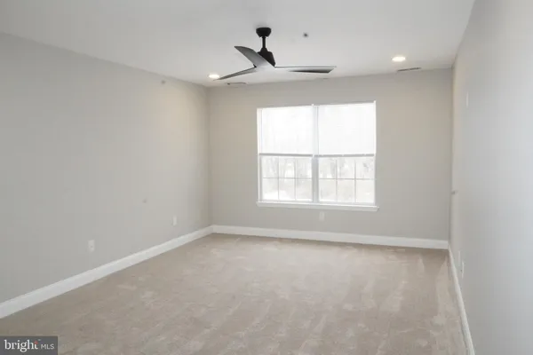 an empty room with a window and a ceiling fan