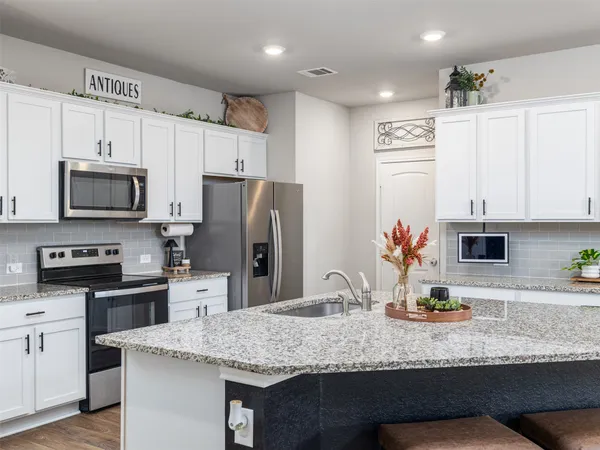a kitchen with stainless steel appliances granite countertop a sink refrigerator and microwave