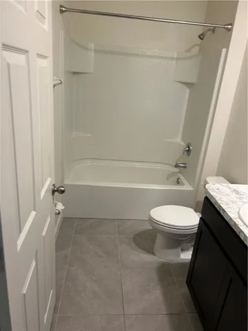a bathroom with a granite countertop bathtub shower and toilet