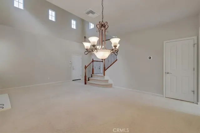a view of a room with a hanging light and kitchen view