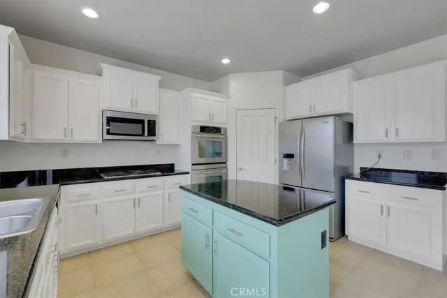 a kitchen with granite countertop a sink a microwave and refrigerator