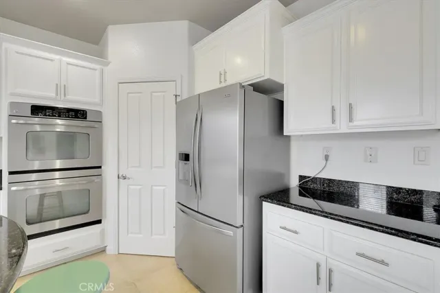 a kitchen with granite countertop white cabinets and stainless steel appliances