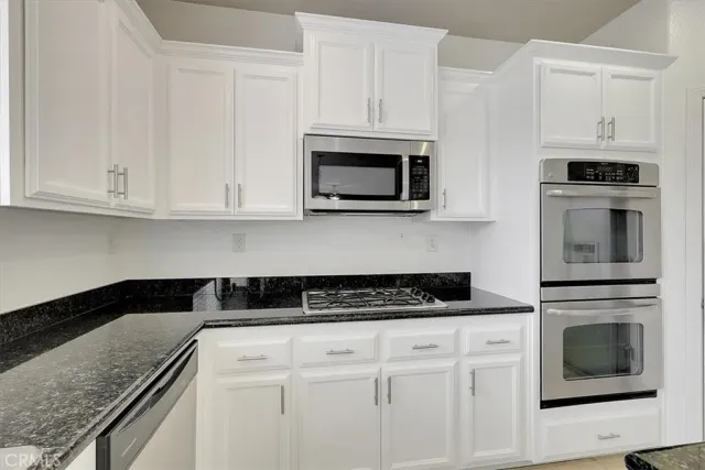 a kitchen with granite countertop white cabinets and stainless steel appliances