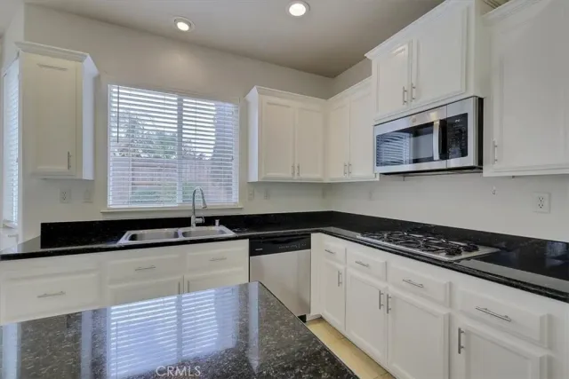 a kitchen with granite countertop white cabinets and black appliances
