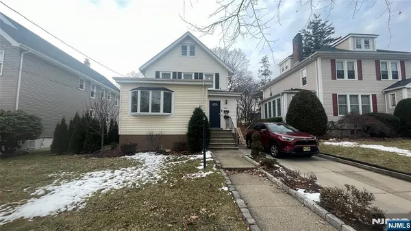 a street view with couple of cars parked in front of house