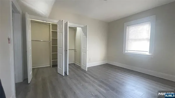 an empty room with wooden floor closet and windows