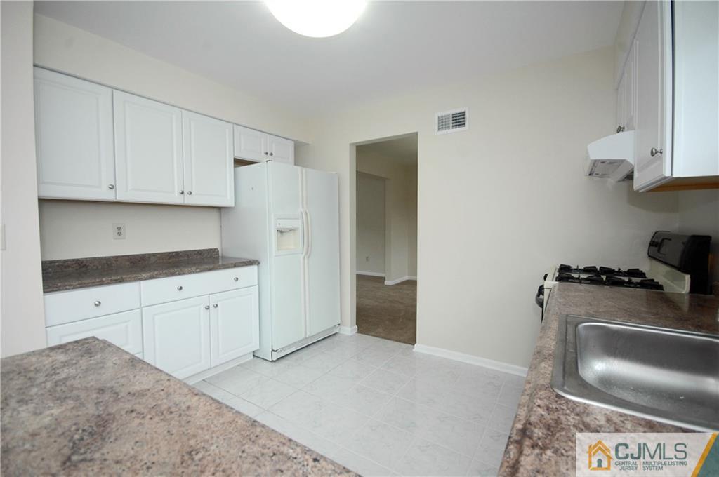 43 Brookside Road Edison, NJ 08817 - Photo 5 of 21 a kitchen with granite countertop a stove top oven a sink a refrigerator and white cabinets
