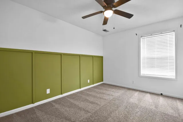 a view of an empty room with a window and a ceiling fan