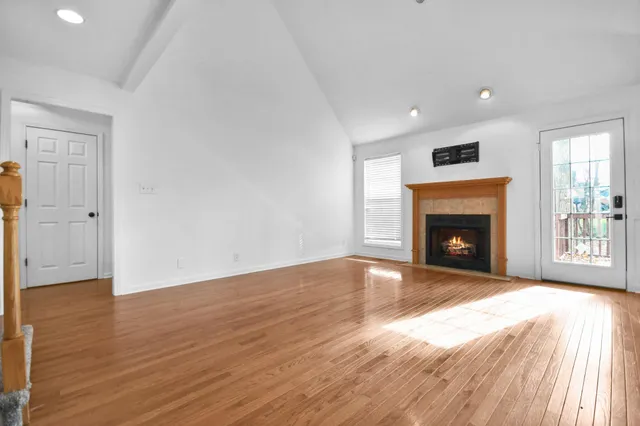a view of empty room with wooden floor and fireplace