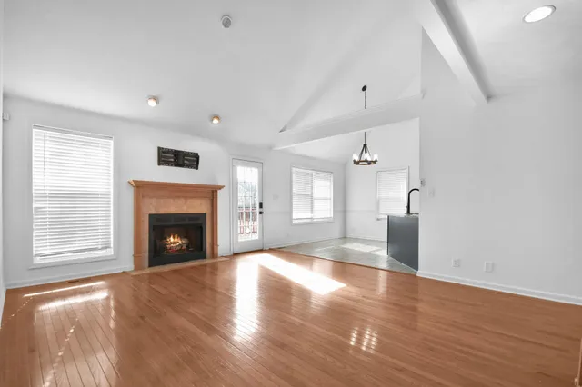 a view of an empty room with wooden floor fireplace and a window