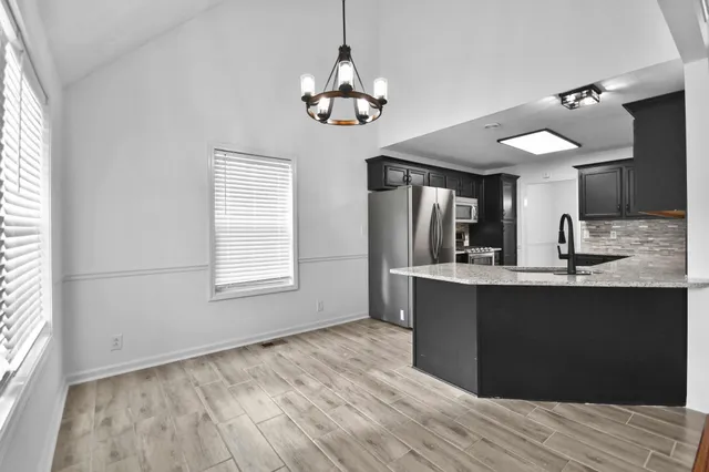 a kitchen with stainless steel appliances granite countertop a sink cabinets and wooden floor