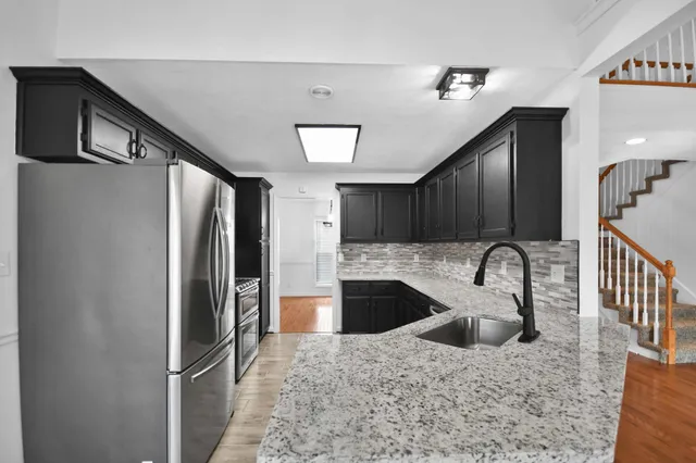 a kitchen with stainless steel appliances kitchen island granite countertop a refrigerator a stove and a sink with wooden floor