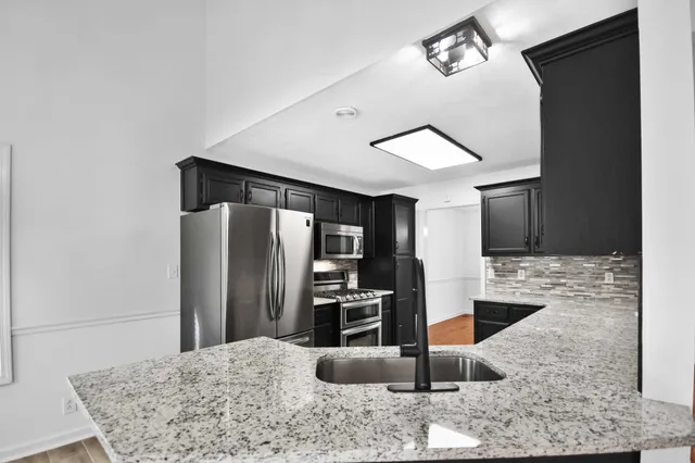 a kitchen with stainless steel appliances kitchen island granite countertop a refrigerator and a sink