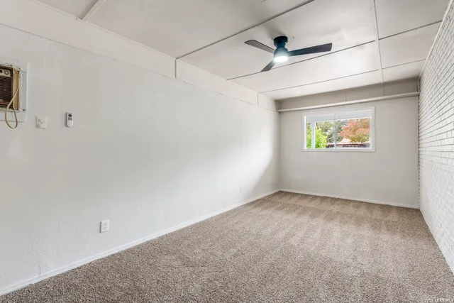 an empty room with a window and a ceiling fan