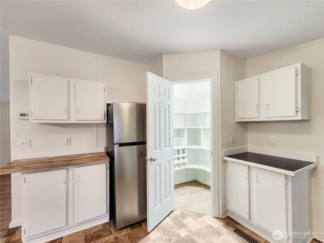 a kitchen with white cabinets and refrigerator