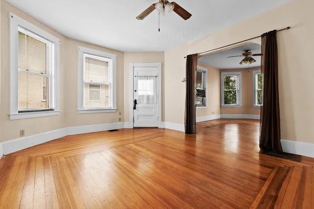 an empty room with wooden floor and windows