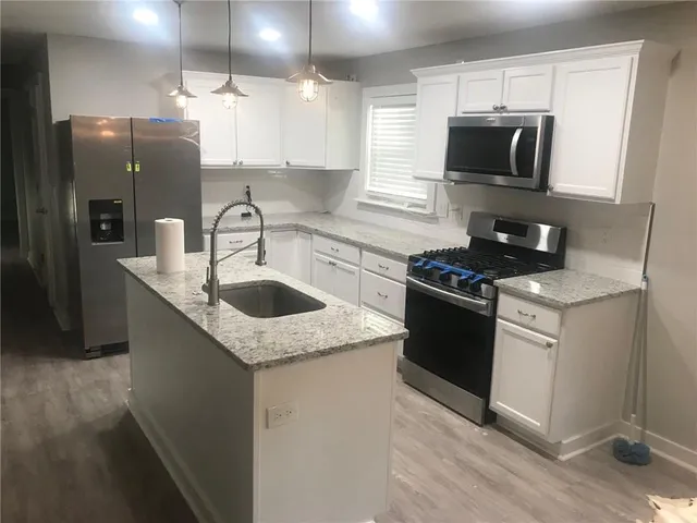 a kitchen with stainless steel appliances granite countertop a sink stove and refrigerator