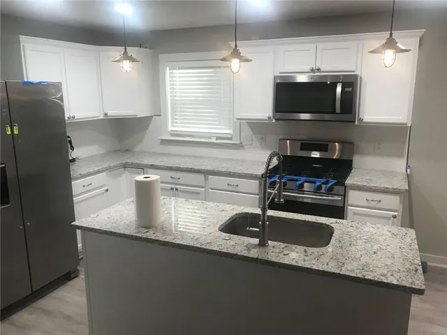 a kitchen with granite countertop a sink and a microwave