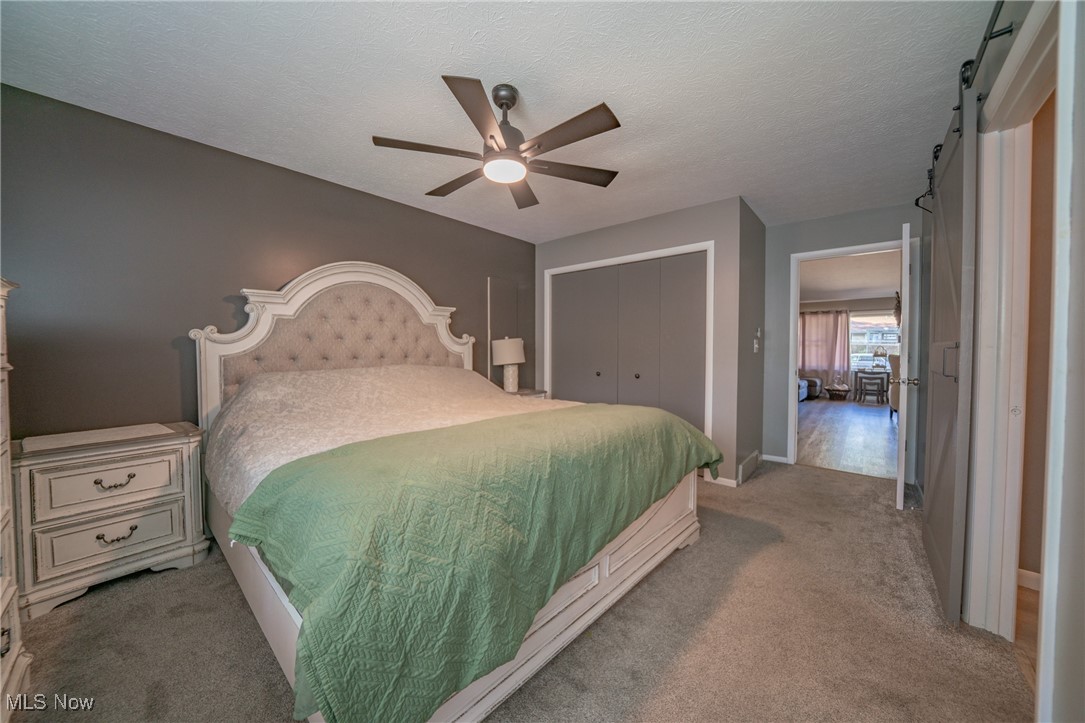 595 Moorfield Road Fairlawn, OH 44313 - Photo 17 of 50 Carpeted bedroom with a barn door, a textured ceiling, a closet, and a ceiling fan