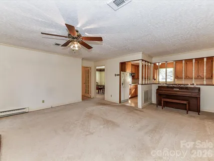 a view of an empty room with a window and a kitchen