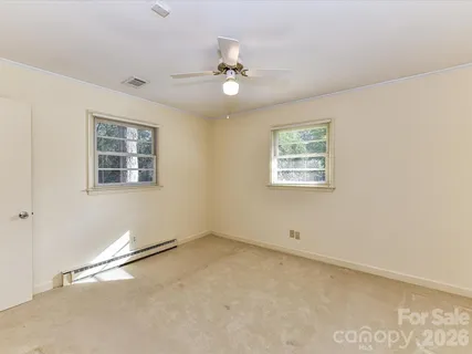 an empty room with windows and ceiling fan
