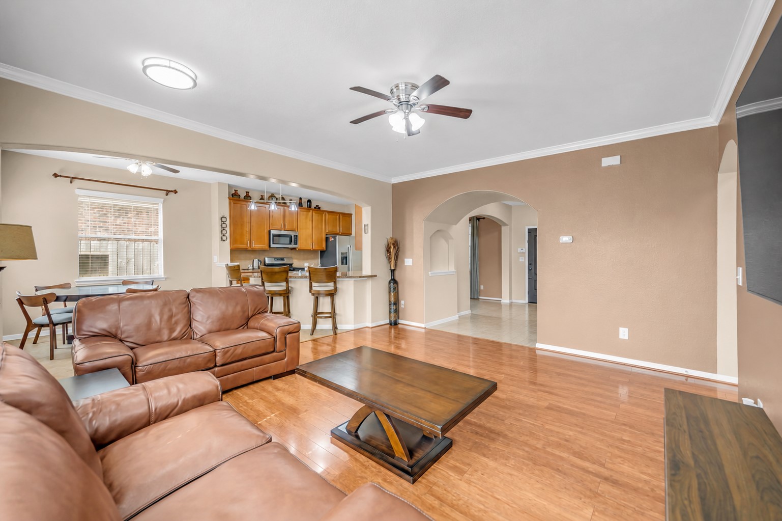 5406 Quarry Ridge Road Richmond, TX 77407 - Photo 18 of 36 Spacious open-concept family room with hardwood floors, abundant natural light, and seamless views into the kitchen and breakfast area, creating an inviting space for everyday living and effortless entertaining.