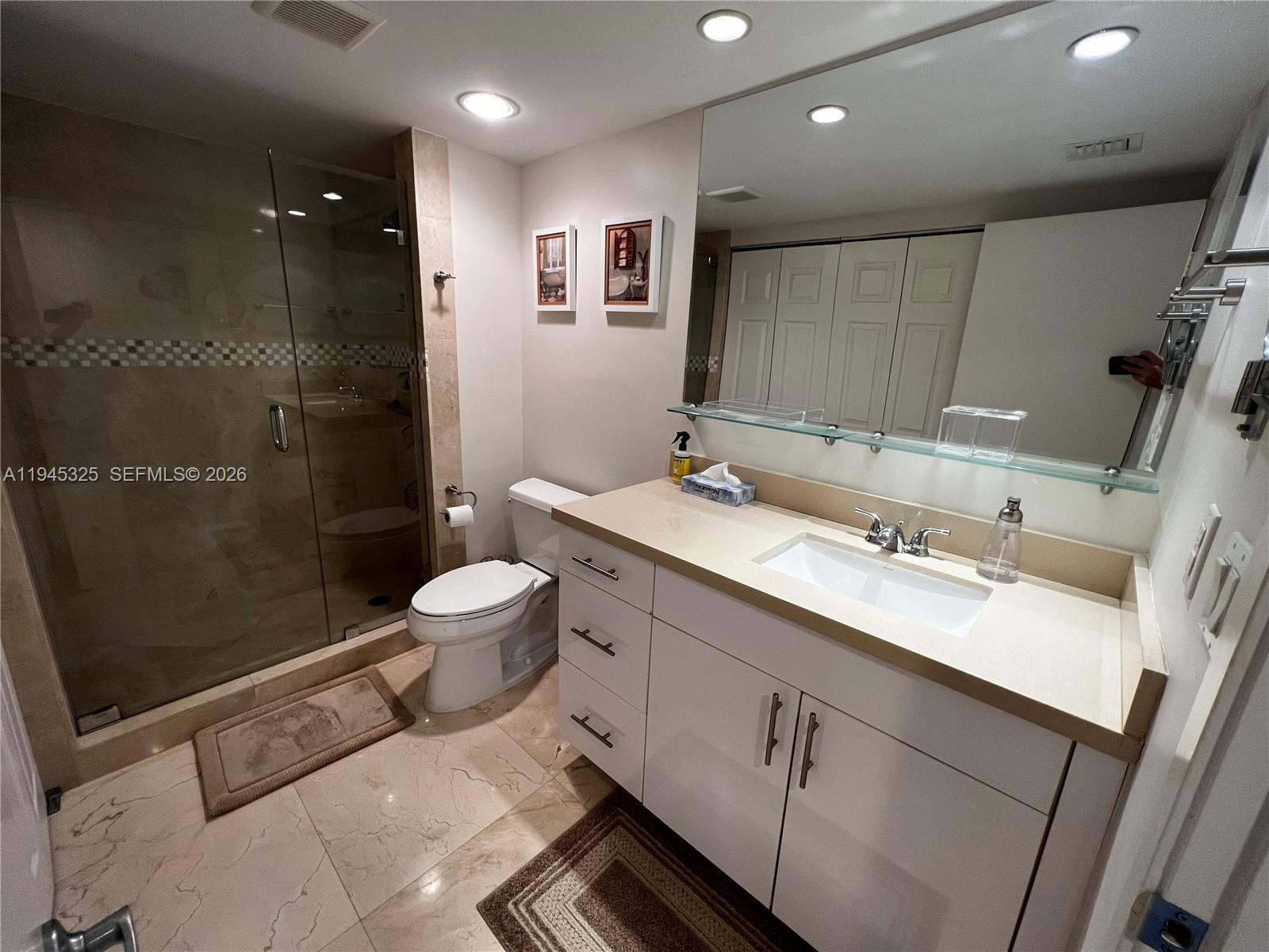 19707 Turnberry Way, Unit 4L Aventura, FL 33180 - Photo 18 of 40 a bathroom with a double vanity sink toilet and shower