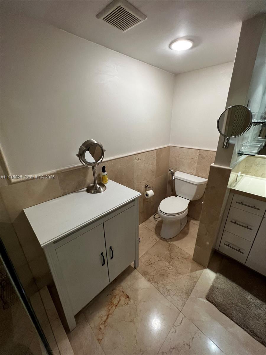 19707 Turnberry Way, Unit 4L Aventura, FL 33180 - Photo 22 of 40 a bathroom with a sink a toilet and mirror