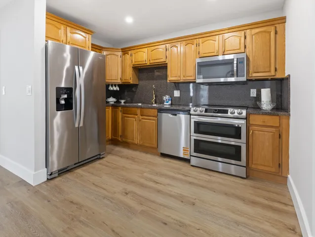 a kitchen with stainless steel appliances granite countertop a refrigerator a stove a sink and a microwave