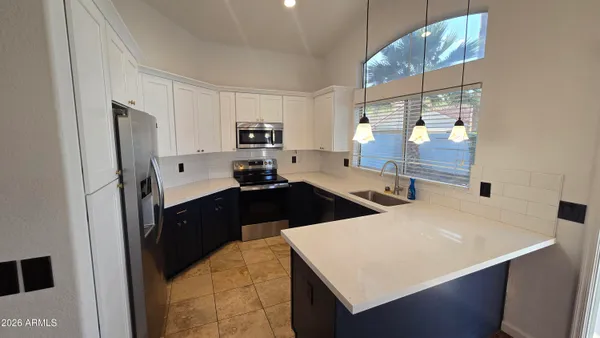 a large kitchen with stainless steel appliances a refrigerator a sink a stove and wooden floors